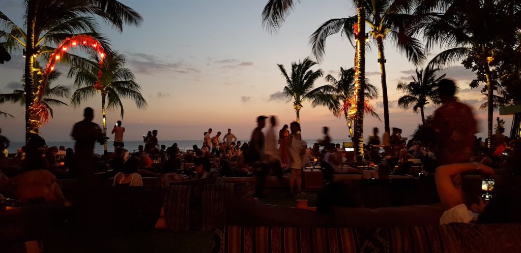 a group of people sitting on a beach at sunset